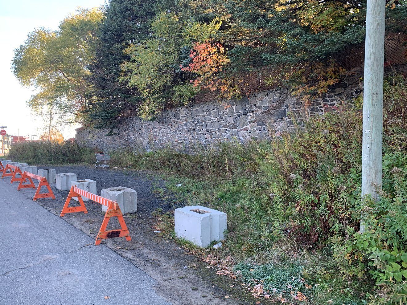 Ancien mur de pierre dégradé, bordé de barrières de chantier, avant les travaux à Shawinigan